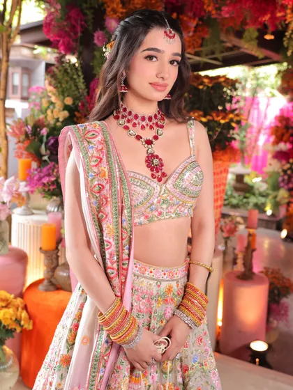 Magic with a touch of sunshine. This Mehendi look is all about fresh, glowing skin and soft makeup that enhances her natural beauty against a vibrant floral backdrop.