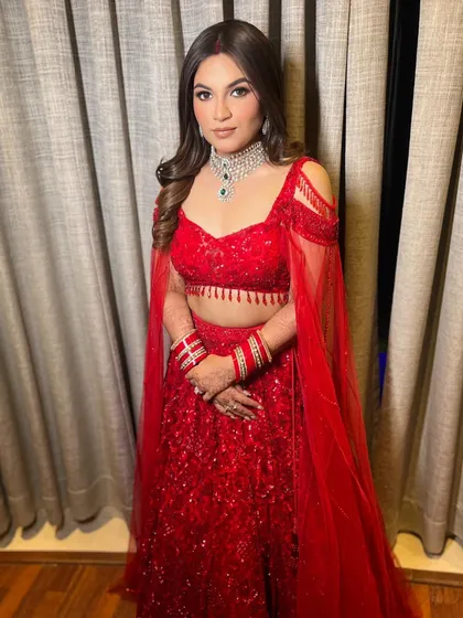 This full-length shot shows how the flowing waves balance the structure of the embellished red lehenga, creating a stunning bridal look.