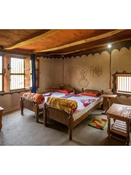 We design spaces that feel like home because they are born from the local culture. This bedroom in a Madhya Pradesh homestay features walls adorned with traditional patterns, simple wooden furniture, and textiles made by local artisans, creating a warm and welcoming retreat.
