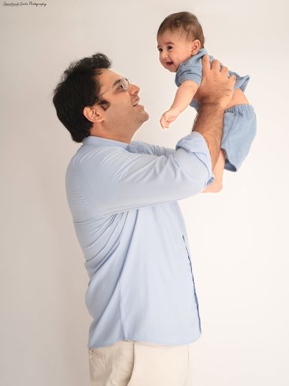 A father's joy as he lifts his baby into the air. This classic dad and baby pose against a simple white background creates a timeless and joyful portrait.