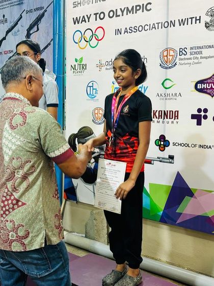A young shooter receives her medal and certificate from G. Susheel, Hon. Secretary of the Karnataka State Rifle Association, at our open competition.