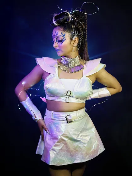 A profile view of the alien character, showing the intricate hairstyle with woven lights and the iridescent quality of the costume.