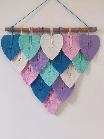 A beautiful pastel macrame leaf hanging. The combination of soft pink, purple, mint, and blue creates a dreamy and calming effect, perfect for a serene space.