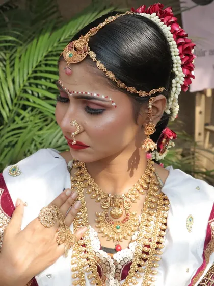 A detailed shot of the Konkani bride's jewellery and the traditional forehead design. The makeup is kept classic with a red lip and defined eyes.