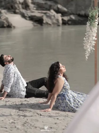 A quiet moment on a custom-decorated beach setup. The simple wooden frames and hanging flowers add a rustic, bohemian touch to the riverside shoot.