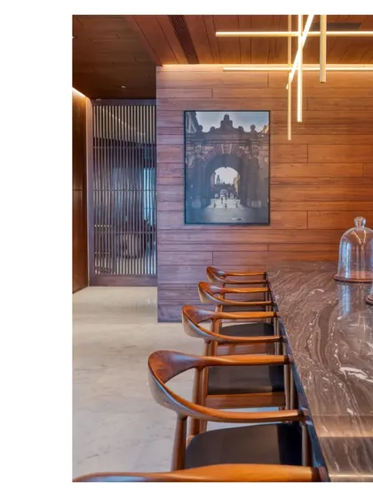 The dining area of the Bombay Penthouse, featuring a bespoke Abu Black marble table and custom lighting. The space is lined with salvaged teak, creating a warm and inviting atmosphere for entertaining.