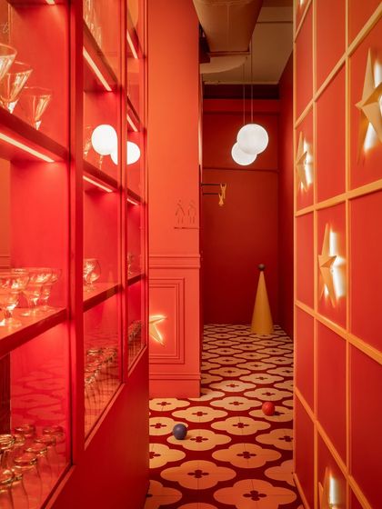 A narrow corridor at Masala is transformed into a journey of light and color. The patterned floor leads the eye through the space, while star-shaped lights and glowing shelves create a sense of discovery and wonder.