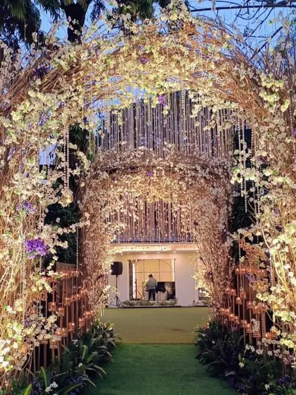 An enchanting entrance tunnel created from rustic branches, white flowers, and sparkling lights. It creates a sense of wonder and anticipation as guests make their way into the event.