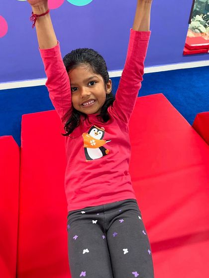 A young girl celebrates with her arms in the air. This look of pure joy and accomplishment is what my program is all about: building confidence one success at a time.