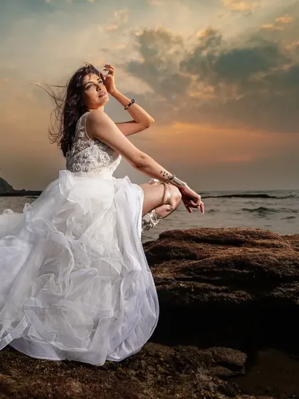 A bridal portrait on the rocks as the sun sets over the ocean. The beautiful colors of the sky and the soft light create a dramatic and romantic mood for this stunning shot.