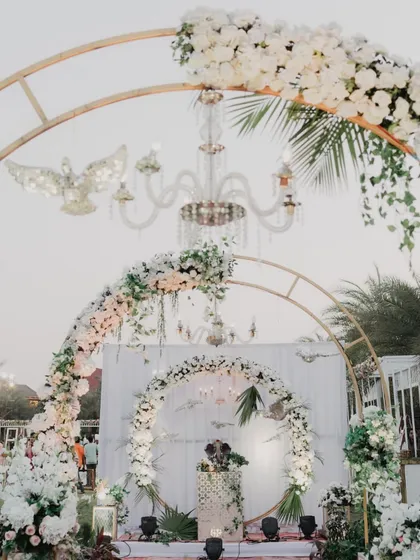 A beautiful photo-op spot with a floral arch and a crystal chandelier, part of our all-white, ethereal wedding theme.