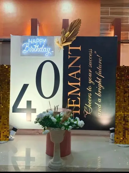 A sophisticated and modern 40th birthday backdrop. This minimalist design features a bold '40', a personalized message, a small neon sign, and two shimmering gold sequin pillars.