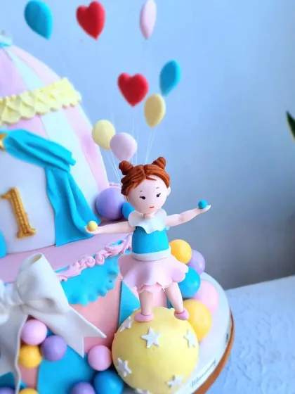 A close-up of the hand-sculpted acrobat figurine on the pastel carnival cake.