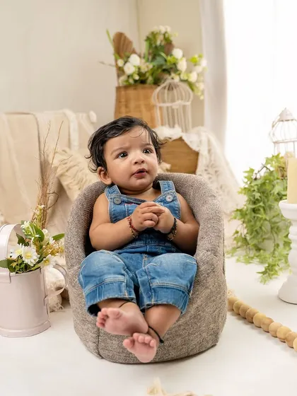 A thoughtful moment in a comfy beanbag chair. The neutral, bohemian-style set creates a calm and beautiful atmosphere for baby portraits.