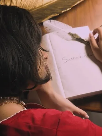 A close-up of me writing in a journal with a quill, a key scene from the 'Svarakshara' music video. This highlights the importance of the written word in my creative process.