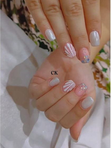 A simple and sweet set with white polish, a 3D shell accent, and a touch of glitter.