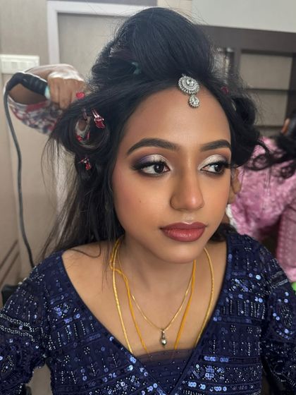 A behind-the-scenes shot of Dr. Akshara's reception makeover. This photo captures the hairstyling process, with her dramatic eye makeup already complete.