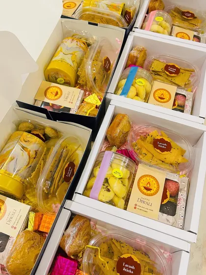 A look at some of the Diwali hampers being assembled in my kitchen. You can see the variety of items, from cookies and cakes to savory sticks, all packed and ready to go.