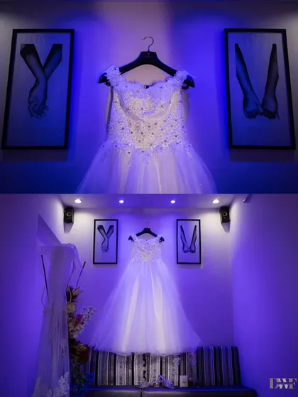 A creative shot of the bride's beautiful white wedding gown, elegantly displayed before the ceremony. The lighting and composition build anticipation for her entrance.