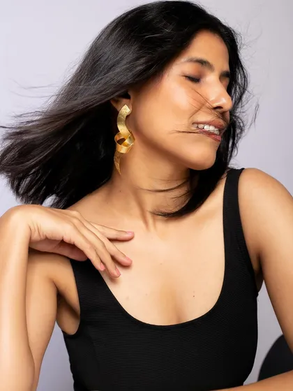This image captures the movement and modern design of these serpentine earrings. The candid, happy expression makes the shot feel dynamic and fashionable.