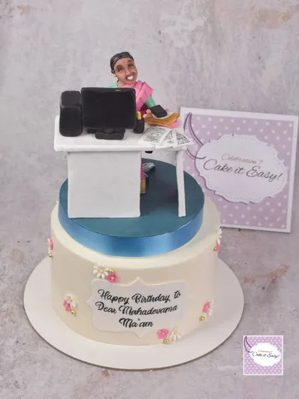 The full two-tier cake with the custom work desk topper. The simple floral design on the bottom tier complements the detailed work on top.