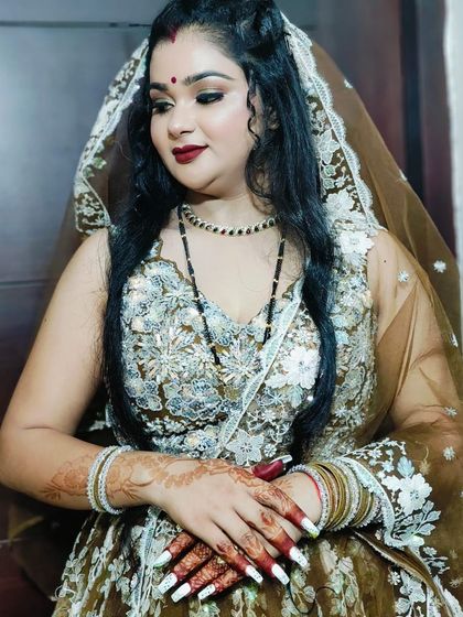 A close-up portrait of the client in her brown lehenga, showing her beautiful makeup and simple black bead necklace.