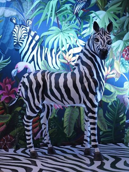A closer look at the zebra statue standing proudly in front of the jungle backdrop. Such life-like props are key to making a themed event feel truly believable and memorable.