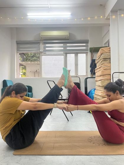 Another pair finds their balance in a partner boat pose, demonstrating the focus and cooperation fostered in our classes.