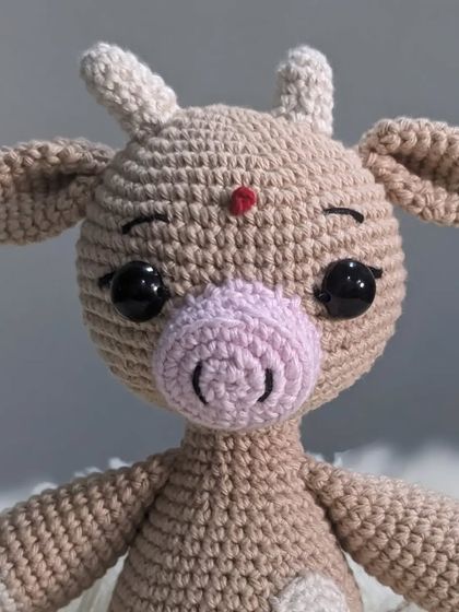 A close-up of the crochet cow's face, showing her sleepy eyes and a little red bindi.