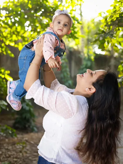 A mother joyfully lifts her daughter into the air. We love capturing these dynamic and loving interactions during our family photoshoots.