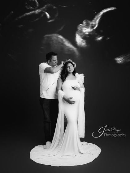 A creative black and white portrait. The partner places a crown on the mom-to-be's head, with a sonogram image edited into the background, symbolizing the new life they are waiting for.