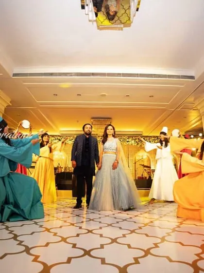 A serene Sufi-themed couple entry. The couple stands in the center as whirling dervishes in colorful costumes create a circle of tranquil movement around them.