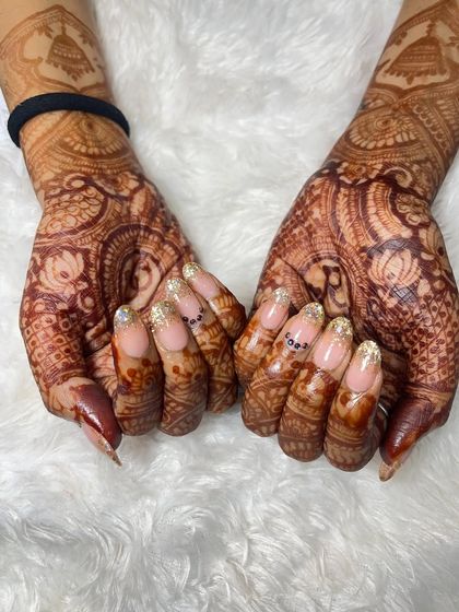 This photo shows the full bridal look with the glitter ombré extensions. The design is crafted to complement the intricate patterns of her mehndi, creating a cohesive and beautiful bridal look.