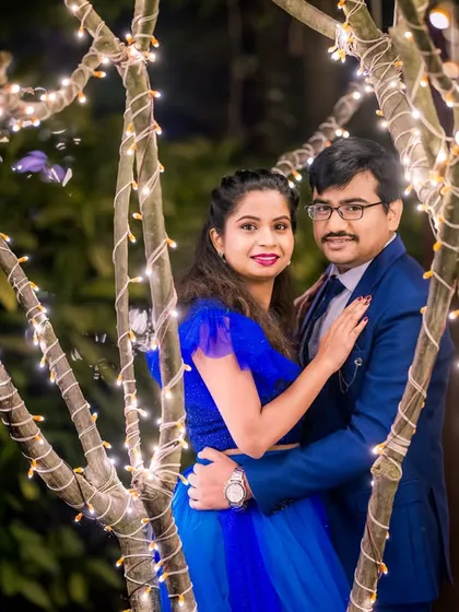 A sweet couple's portrait taken between the branches of a tree wrapped in fairy lights, offering a unique and intimate perspective.