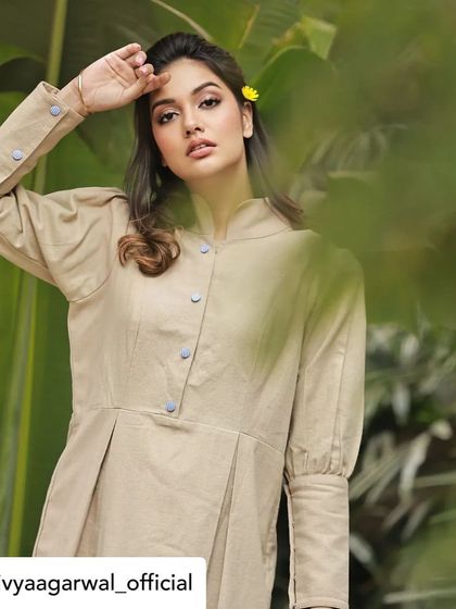 A thoughtful pose from Divya Agarwal in our beige tunic dress. The simple yellow flower in her hair complements the outfit's earthy and natural tone.