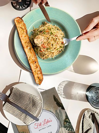 A classic plate of Aglio e Olio spaghetti served with a long, crispy piece of garlic bread. It's a simple, elegant, and flavorful meal.