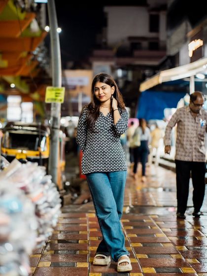 A full-length portrait on a wet street at night. The reflections on the pavement add an extra layer of visual interest.