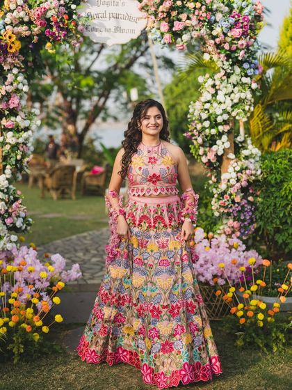 The full picture. Yogita standing under a floral arch, looking every bit the part of a garden princess. Her makeup was designed to be light and fresh for the daytime event.