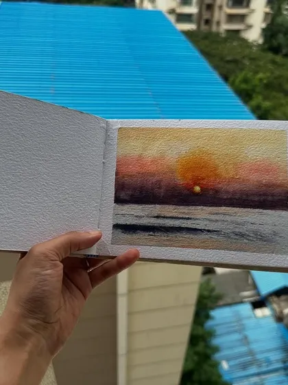 Holding my watercolour sunset painting against the backdrop of city buildings. A little piece of natural beauty in an urban environment.