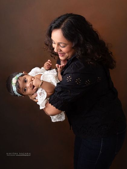 A mother holds her eight-month-old daughter, their playful interaction creating a dynamic and joyful portrait. These are the moments you'll want to remember.