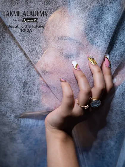 An artistic shot of the finished nail art, partially obscured to create a sense of mystery and elegance. This highlights the beauty and detail of the gold and pink design.