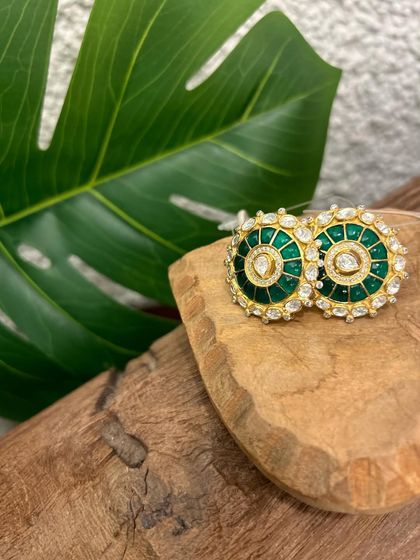 A pair of classic round studs, elevated with rich green meenakari work and a halo of sparkling kundan stones.