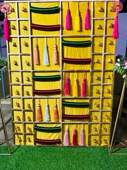 An angled shot of the 'Bangla' backdrop, showing the texture of the yellow fabric and the colourful hanging tassels.
