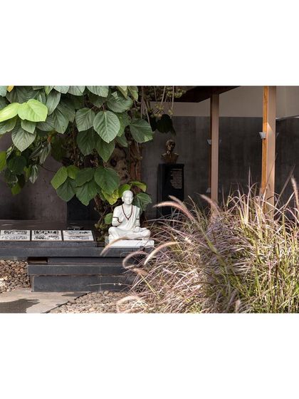 A statue of Buddha sits in a contemplative corner of the museum garden, nestled among plants and stone benches. The landscape includes many such moments for quiet reflection.