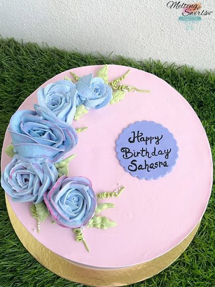A top-down view of a beautiful floral cake with hand-piped whipped cream roses in shades of blue and pink.