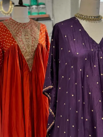 A close-up of two distinct styles. The orange kurta features a heavily embroidered V-neck, while the purple kaftan offers a more relaxed fit with scattered motifs.