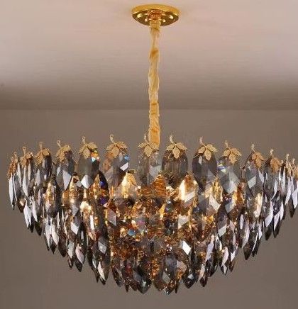 A beautiful chandelier featuring smoked crystal leaves on a golden frame. This piece hangs like a luxurious canopy, adding a touch of glamour and sophisticated sparkle to living rooms or bedrooms.
