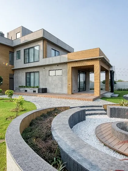 For this modern farmhouse in Sonipat, the design integrates the structure with its natural surroundings. I used a mix of textured concrete and warm brick, complemented by a sunken fire pit and curved landscaping to create a seamless indoor-outdoor living experience.