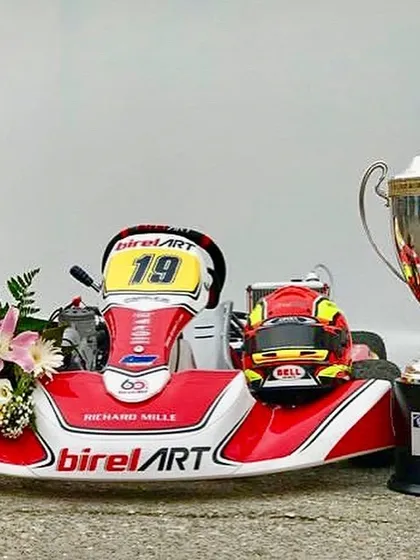 A detailed shot of the championship-winning Birel ART kart next to the prestigious FIA KZ World Championship trophy.