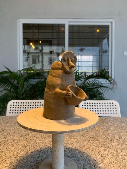 A primitive, expressive sculpture of a figure holding a bowl. This piece, made by a student, has a raw, ancient quality to it.